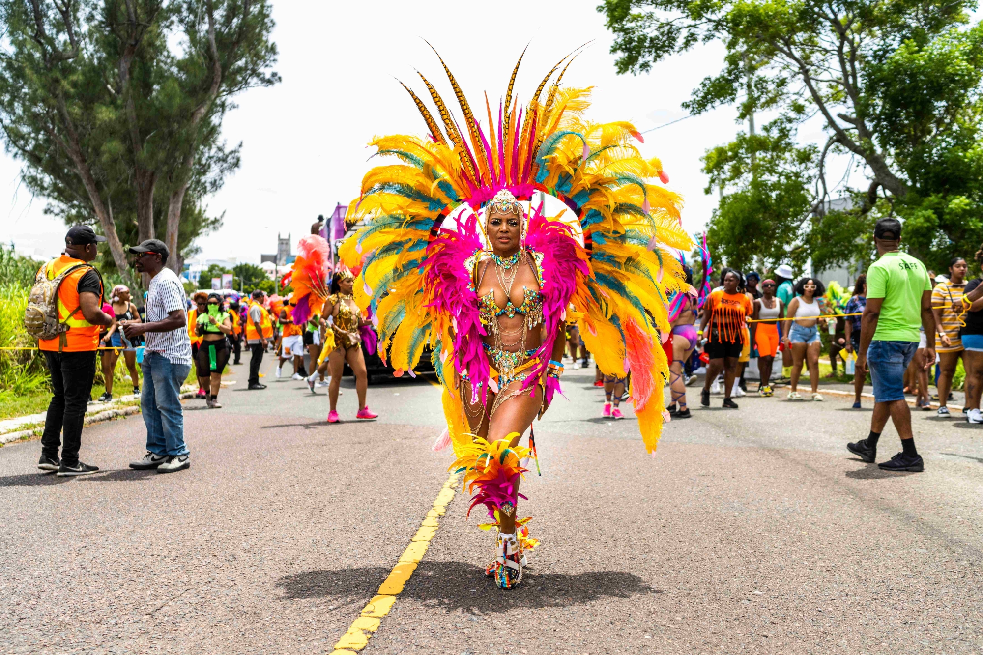 A woman is standing in the road in a colourful feathery costume.