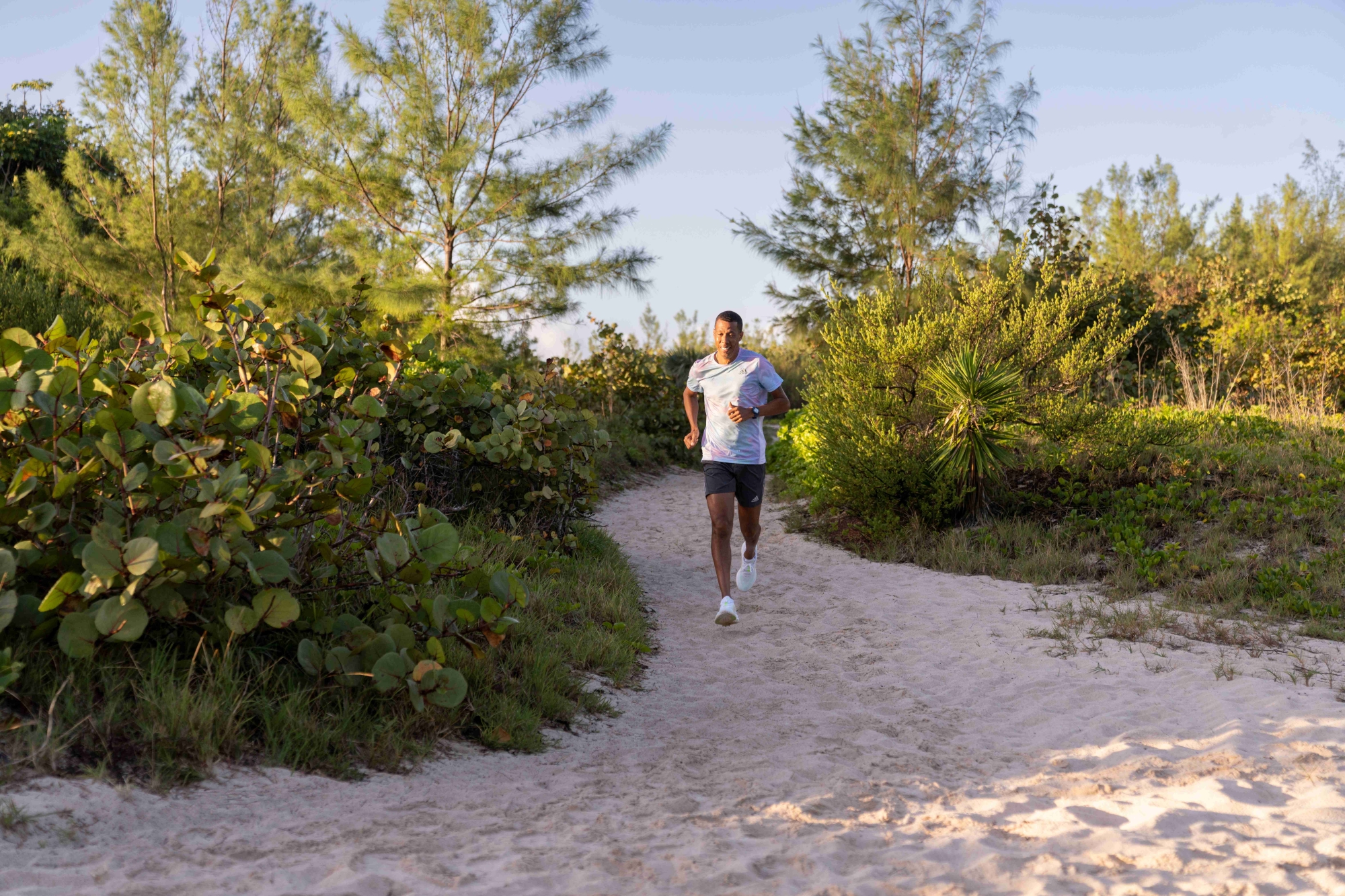 A man is running on a sandy trail.