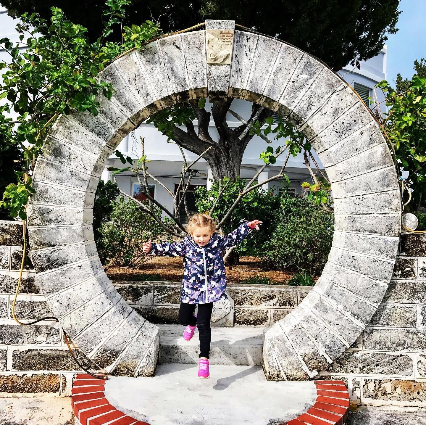 A little girl playing by a stone archway