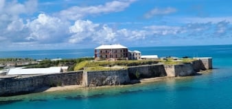 A navy building sits on a hill overlooking the ocean.