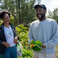 Two people are smiling holding plants